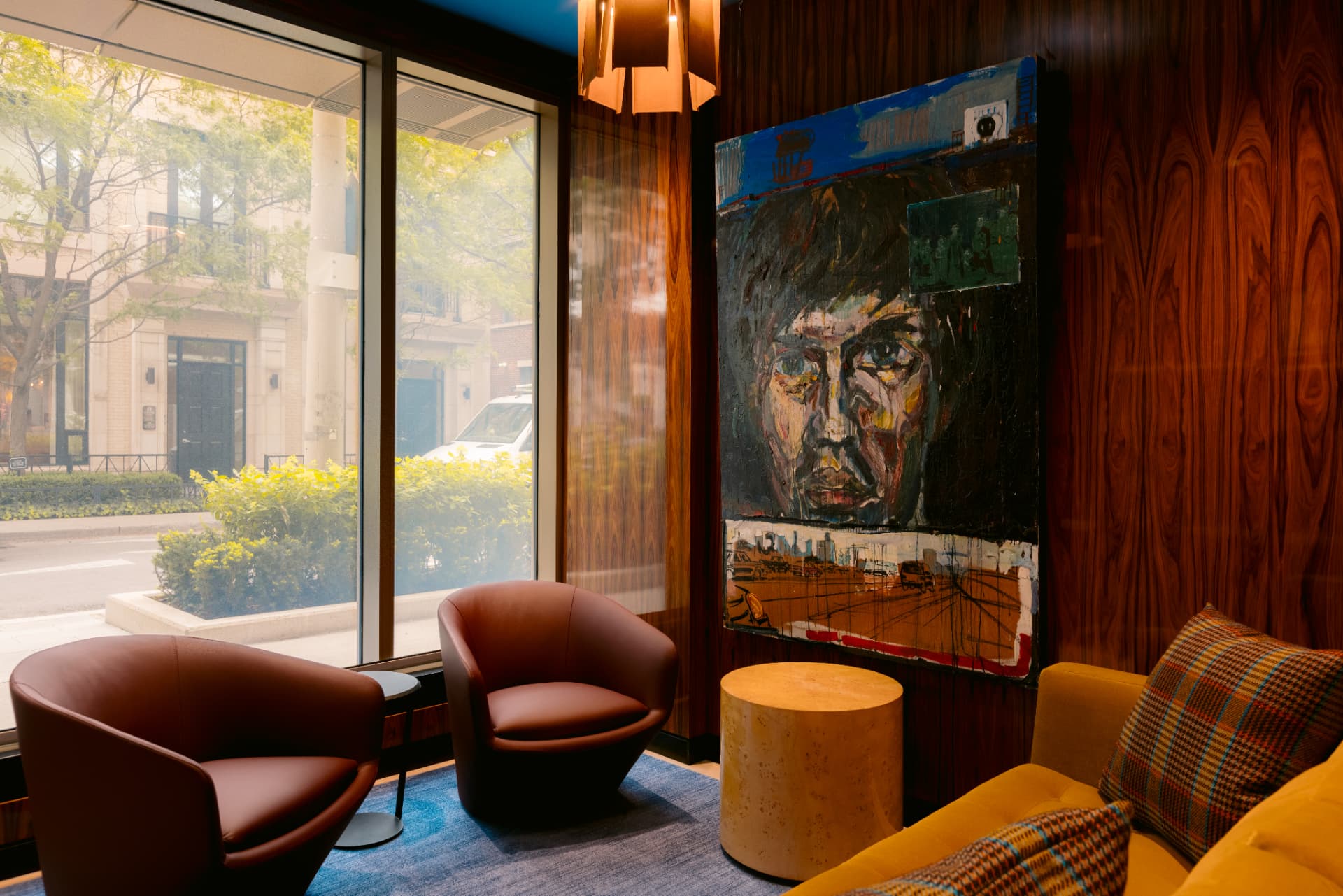 Two leather chairs beneath a large portrait painting, with a window onto Yorkville